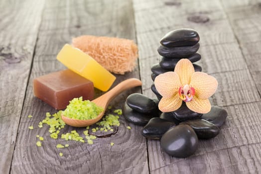Spa with bath salt, hot stones, soaps and loofah on wooden background