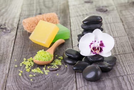 Spa with bath salt, hot stones, soaps and loofah on wooden background