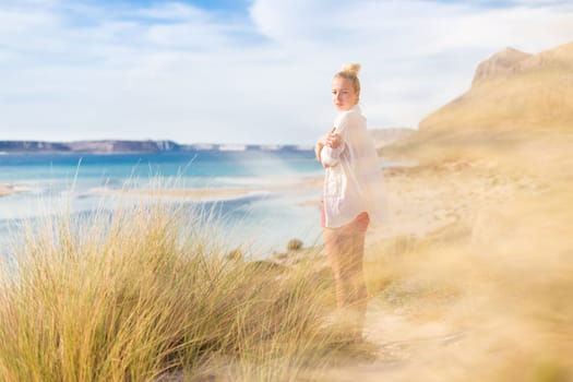 Woman, arms crossed, feeling chilled, enjoying last autumn sun, an beautiful Balos beach. Concept of vacations, freedom, happiness, enjoyment and well being.