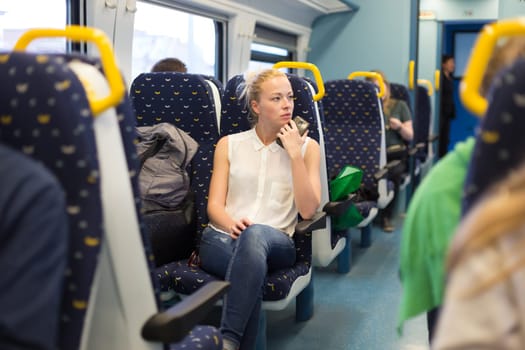 Young woman looking trough window while traveling by train.