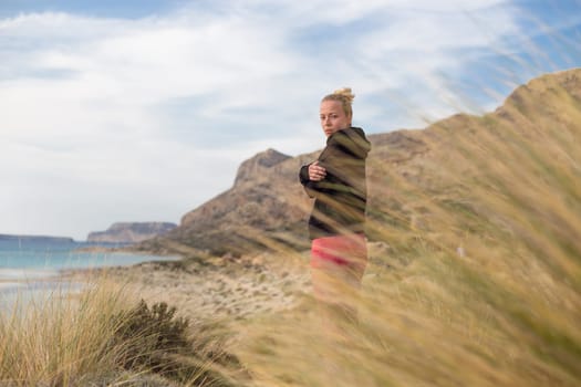 Woman, arms crossed, feeling chilled, enjoying last autumn sun, an beautiful Balos beach. Concept of vacations, freedom, happiness, enjoyment and well being.