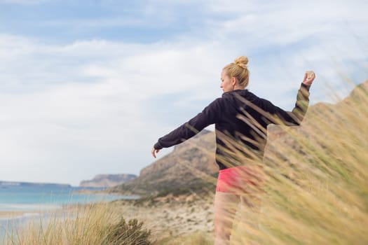 Woman, arms crossed, feeling chilled, enjoying last autumn sun, an beautiful Balos beach. Concept of vacations, freedom, happiness, enjoyment and well being.