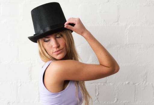 Blonde woman with cylinder looks seductively over her shoulder