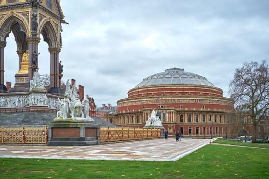 LONDON, UK - DECEMBER 17: People walking past Albert Memorial statues with Royal Albert Hall in the background, in Kensington Gardens. December 17, 2014 in London.