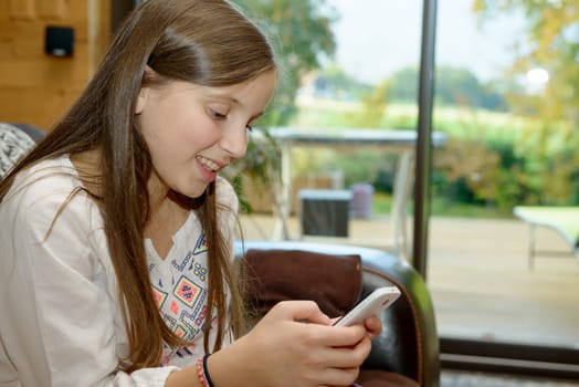 young teenager girl on the sofa sends a text message