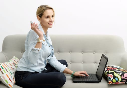 smiling woman shopping online with credit card and laptop.