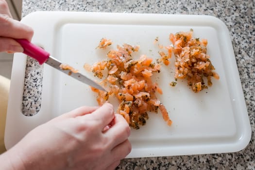 Cut raw smoked salmon into cubes on a cutting board
