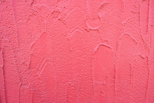 Wall of a façade with coarse plaster in red
