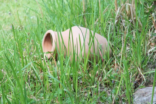 . A terracotta amphora lies in the green grass.