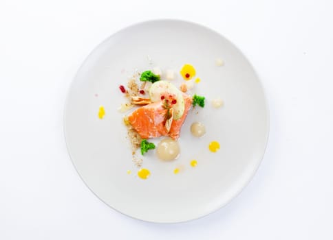 Molecular modern cuisine red fish in a dish with beautiful garnish close up. Isolated