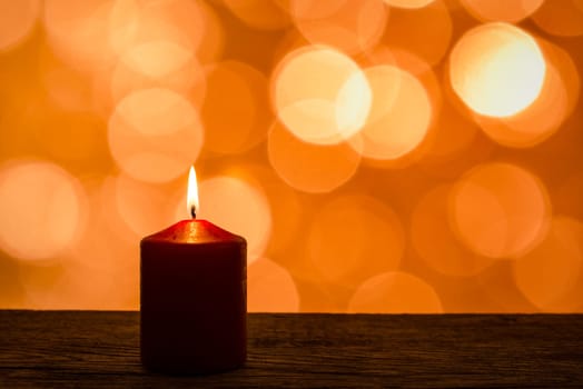 Candle with flame and lights as bokeh in the background