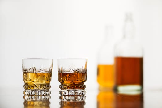 Whiskey glasses with bottles on white background