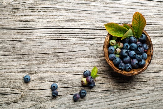 Fresh blueberries with green leaves on wooden background