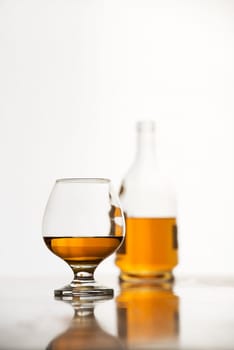 Cognac in glass with bottle on white background