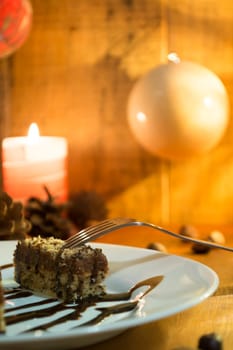 Chocolate cake with walnut cut into squares served with candles with christmas decoration