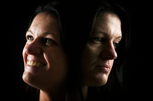 Double exposure head of a middle-aged woman with happy and sad facial expression against a black background.