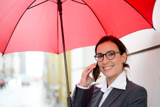 Businesswoman with smartphone and umbrella
