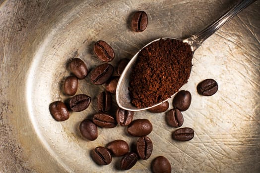 Fresh ground Coffee in spoon on plate close up.