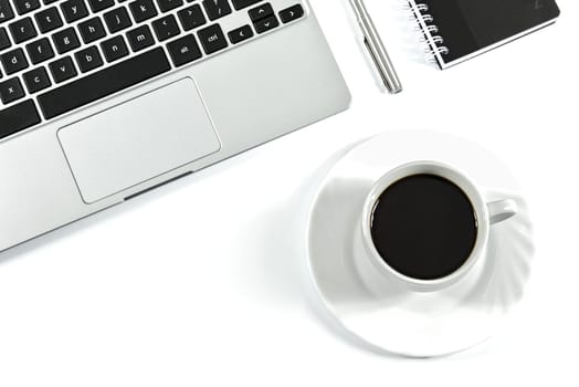 Pen and notebook close to the laptop and coffee in a modern office