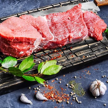 Raw beef steak and laurel branch on cutting board