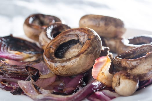 Roasted mushrooms with onion on white plate