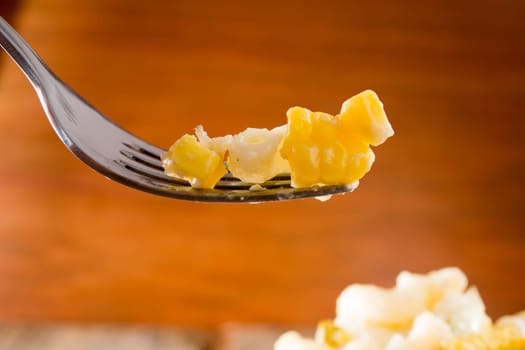 Close up of a fork and salad with pasta, yellow corn and Italian seasonings.