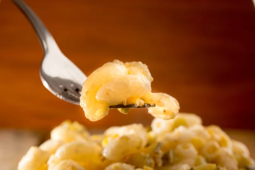 Close up of a fork and salad with pasta, yellow corn and Italian seasonings.