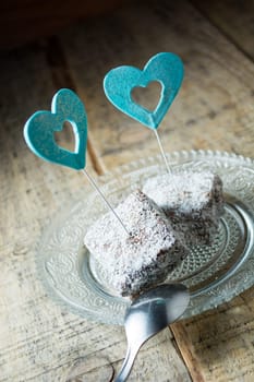 Close up of chocolate cakes with coconut flour on the glass plate with blue ornaments