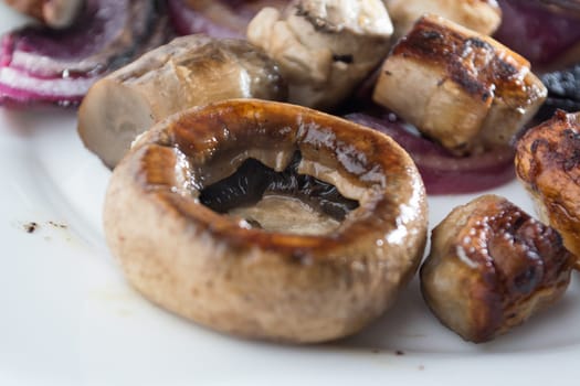 Roasted mushrooms with onion on white plate