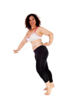 A pretty woman in exercise outfit standing and measuring her stomach.smiling she is happy, isolated for white background..