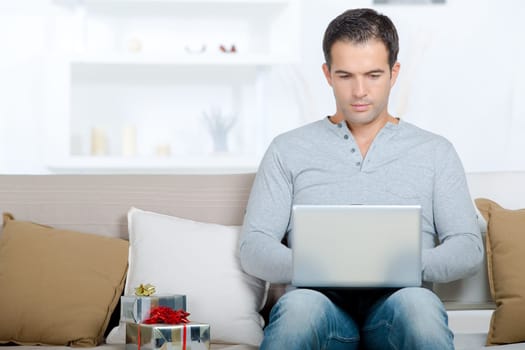 happy man sitting with laptop computer on sofa