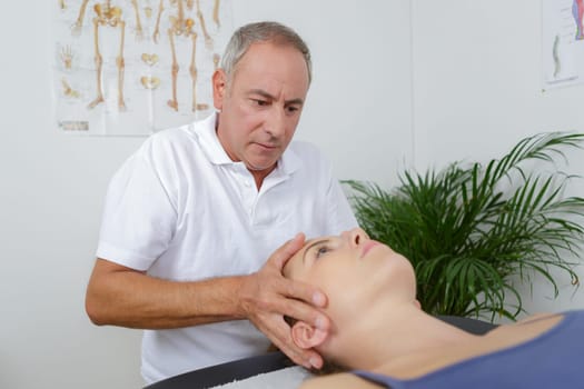 physiotherapist massages holding male clients head