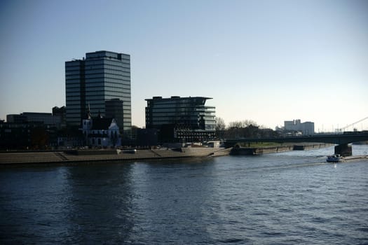The Lanxess skyscraper at the Severins Bridge in Cologne with a passing cargo ship.