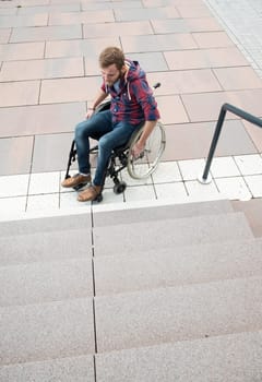 young disabled man in wheelchair in front of stairs from above