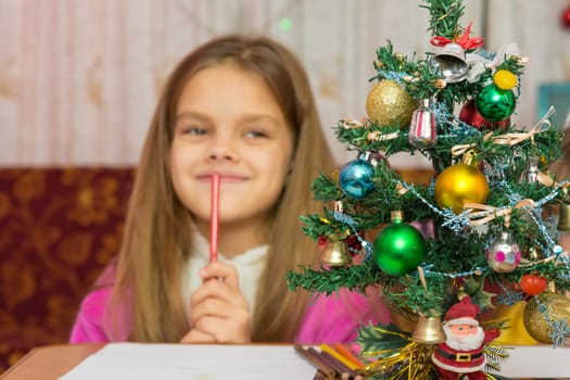 Girl happily thinking about a gift for the new year, focusing on a fur-tree