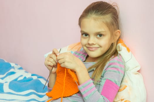 The girl knits on the needles, and looked into the frame