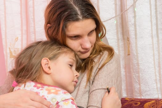 Sad five year old girl hugging her mother