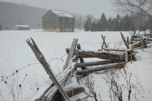 An ontario bank barn with split cedar rail fence in the snow in winter