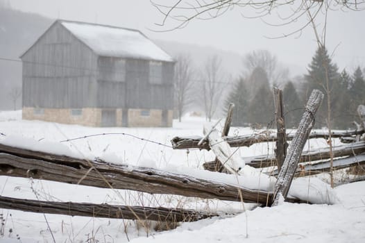 An ontario bank barn with split cedar rail fence in the snow in winter