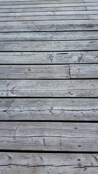 Silvery worn wood planks run horizonally as a background with character. Top planks recede into distance.