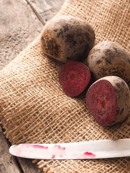 Beet root on burlap and wooden table with an old knife