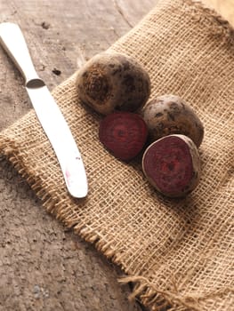 Beet root on burlap and wooden table with an old knife