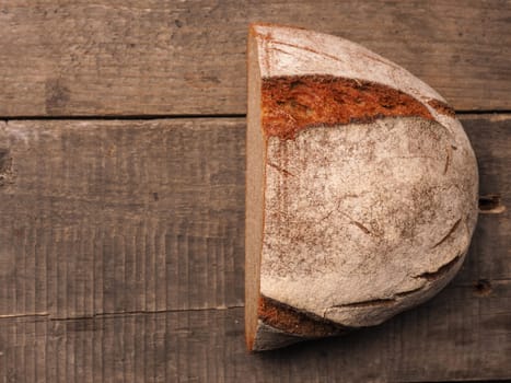 Half of a delicious rustic bread on a wooden background with space for text