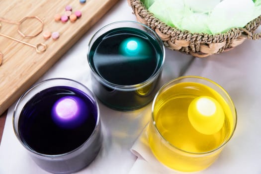 Three eggs in cups of dye for Easter