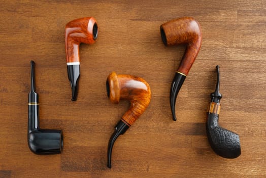 Collection of five pipes on wooden background