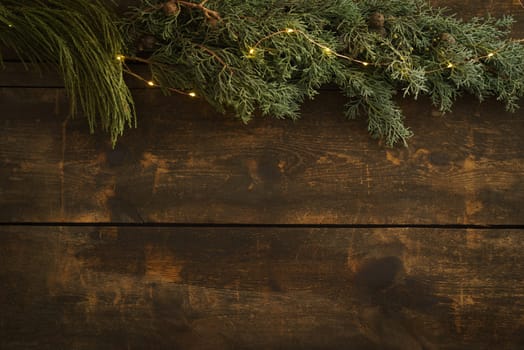 Wooden Christmas background with fir green, fir cones and fairy lights