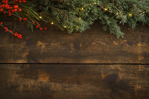 Wooden Christmas background with fir green, fir cones and fairy lights