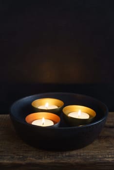 Three votive candles in copper or golden votive candle holders