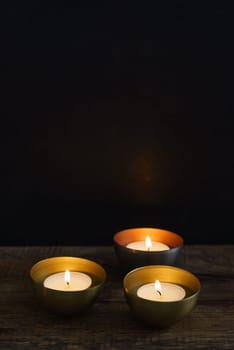 Three votive candles in copper or golden votive candle holders