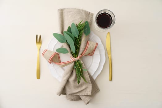 Natural Christmas place setting with golden silverware, eucalyptus and greens